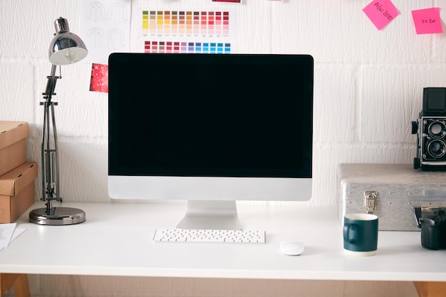 Espace de travail en studio créatif avec bureau et ordinateur devant le mur avec des dessins de mode