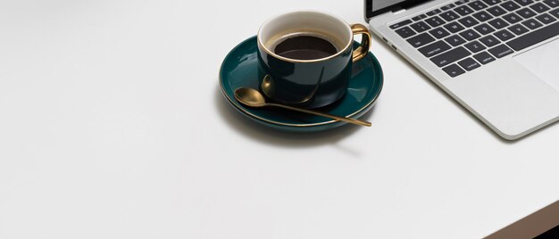 Espace de travail avec tasse à café en céramique verte, ordinateur portable et espace de copie sur tableau blanc