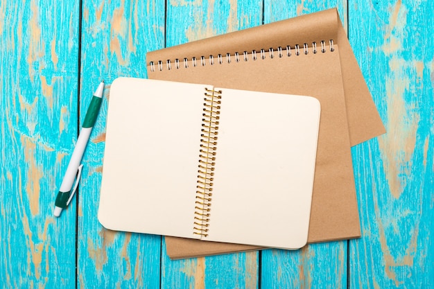 Espace de travail vue de dessus avec un cahier vierge et un stylo sur fond de table en bois