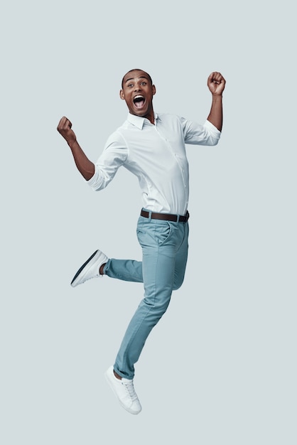 Photo espiègle. beau jeune homme africain faisant une grimace en planant sur fond gris