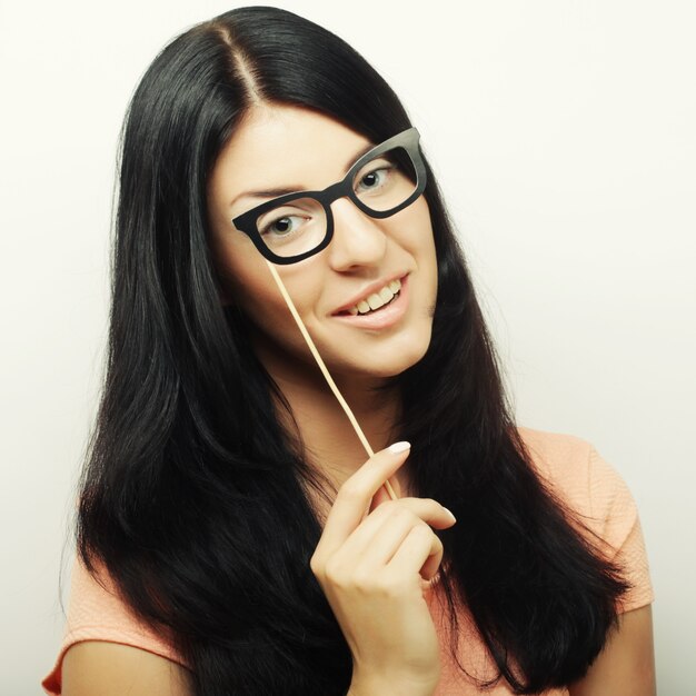 Espiègles jeunes femmes tenant une lunettes de fête.