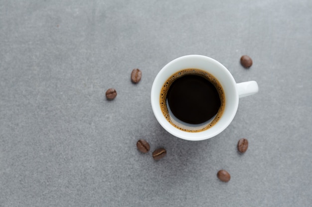 Espresso savoureux dans une tasse avec des grains de café. Vue d'en-haut. table en béton.