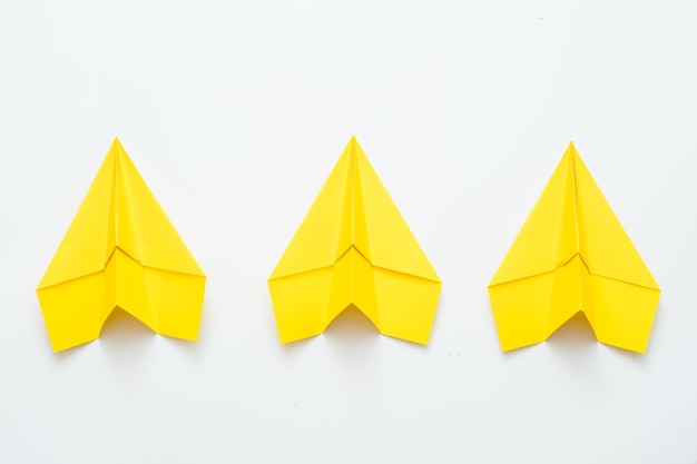 Esprit d'équipe et ambition. Trois avions en papier jaune isolés sur blanc.