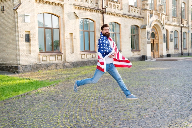 Esprit patriotique. Homme patriotique sautant avec le drapeau américain. Jour de l'indépendance. Citoyen patriotique hipster barbu. Heureux et fier. Rejoignez la célébration. Guy patriotique exprimant le bonheur dans la rue.