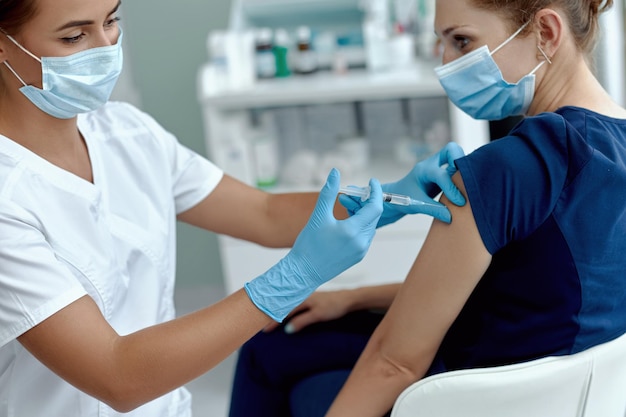 Essai clinique pour le nouveau vaccin Covid19 pendant la pandémie mondiale femme portant un masque médical recevant une injection à l'hôpital