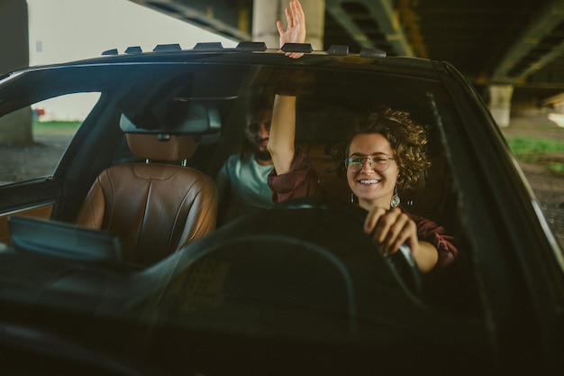 Essai routier Femme aux cheveux bouclés conduisant une voiture et ayant l'air satisfaite