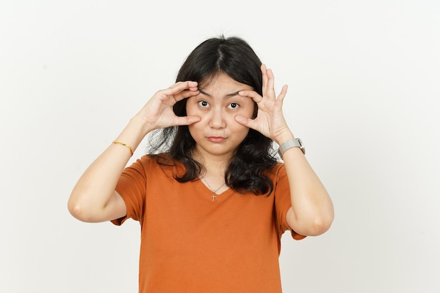 Essayer d'ouvrir les yeux de la belle femme asiatique portant un t-shirt orange isolé sur fond blanc