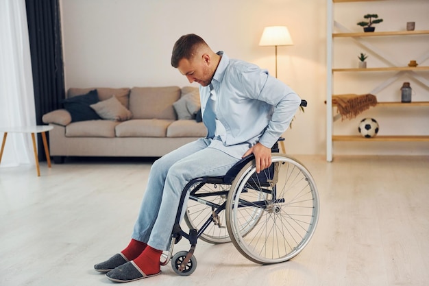 Essayer de se lever Un homme handicapé en fauteuil roulant est à la maison