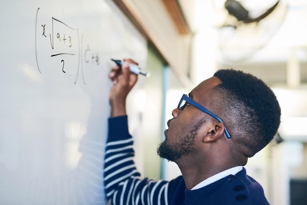 Photo essayez jusqu'à ce que vous réussissiez photo recadrée d'un jeune homme écrivant sur un tableau blanc dans une salle de classe