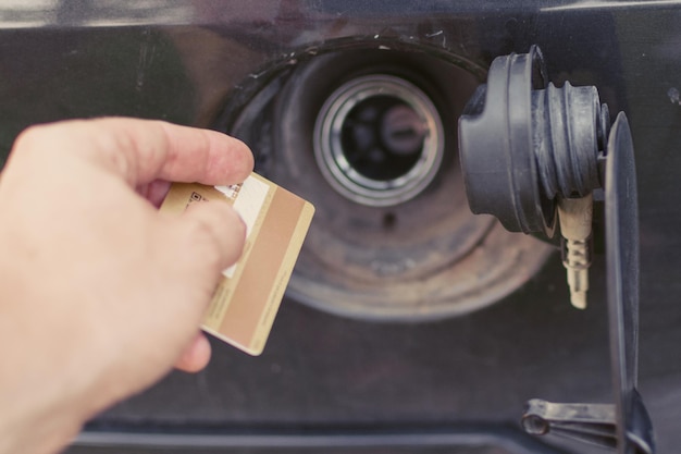 Essence chère Dépenses en essence Une trappe d'un réservoir de moteur et une carte de crédit dans la main d'un homme