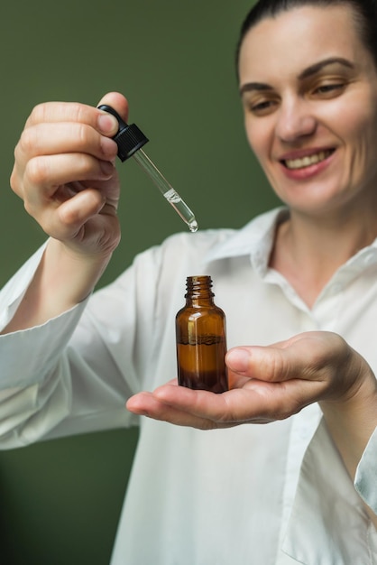 Essence avec une pipette entre les mains d'une femme de race blanche