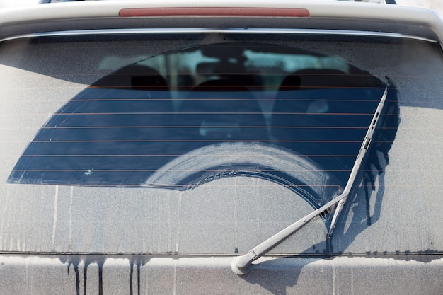 L'essuie-glace nettoie une lunette arrière sale d'une voiture