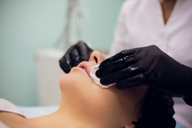 Essuyez avec un visage de serviette stérile. Jeune femme recevant des traitements dans les salons de beauté.