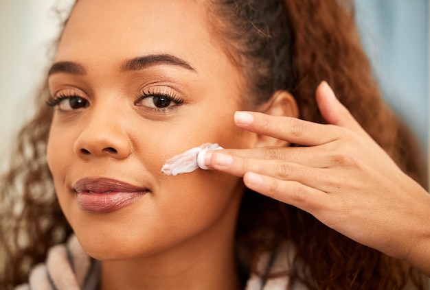 C'est ainsi que je le garde doux et éclatant Photo recadrée d'une belle jeune femme appliquant une crème hydratante sur son visage