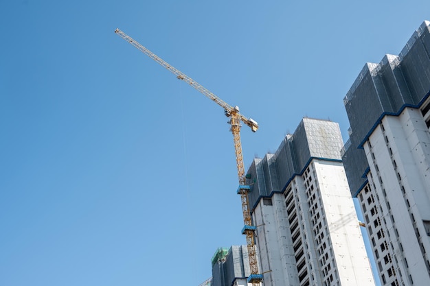 C'est une belle journée avec un ciel bleu et la grue à tour sur les immeubles de grande hauteur de la ville est en construction