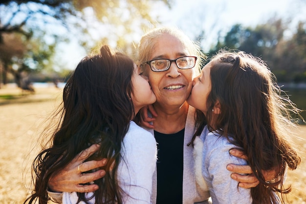 C'est une bénédiction d'avoir des petits-enfants Photo recadrée d'une grand-mère se faisant embrasser sur les joues par ses deux adorables petites-filles