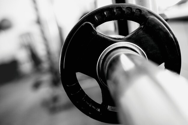 C'est un cou d'haltères avec un disque en gros plan dans une salle de sport vide Mise au point sélective