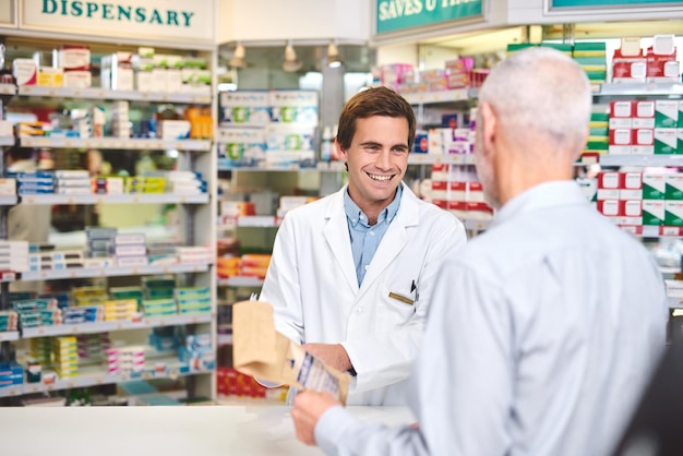 C'est exactement ce dont vous avez besoin Photo recadrée d'un beau jeune pharmacien masculin aidant un client à la pharmacie