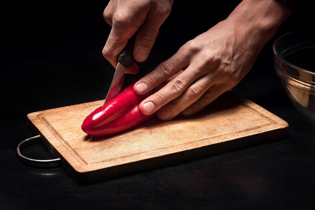 C'est gouteux. Gros plan des mains de l'homme, hacher le poivron tout en travaillant comme chef et en cuisinant dans le restaurant.