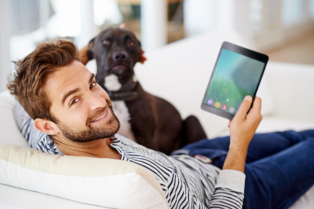 C'est l'un de ces jours où l'on traîne sur le canapé L'homme utilise sa tablette sur son canapé