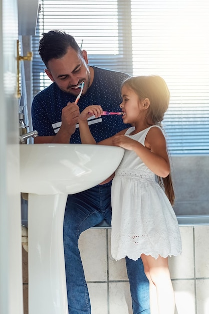 C'est leur habitude quotidienne Photo recadrée d'un père et de sa fille se brossant les dents ensemble au lavabo de la salle de bain