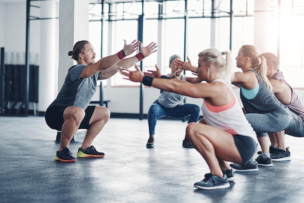 C'est lui qui vous met en forme Photo d'un instructeur de fitness travaillant avec un groupe de personnes à la salle de sport