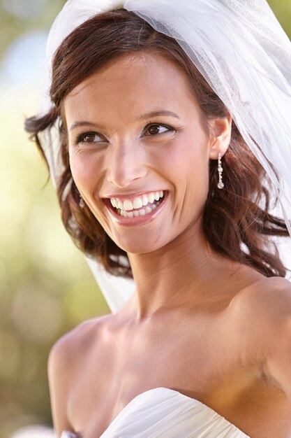 C'est une mariée rougissante Superbe jeune mariée regardant loin dans sa robe de mariée et voile