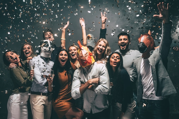 C'est mon année ! Groupe de jeunes portant des masques d'animaux jetant des confettis et ayant l'air heureux