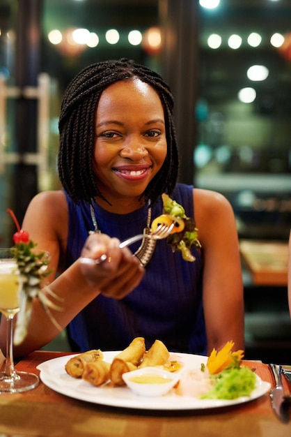 C'est mon endroit préféré pour manger Portrait d'une jolie jeune femme en train de manger un repas dans un restaurant