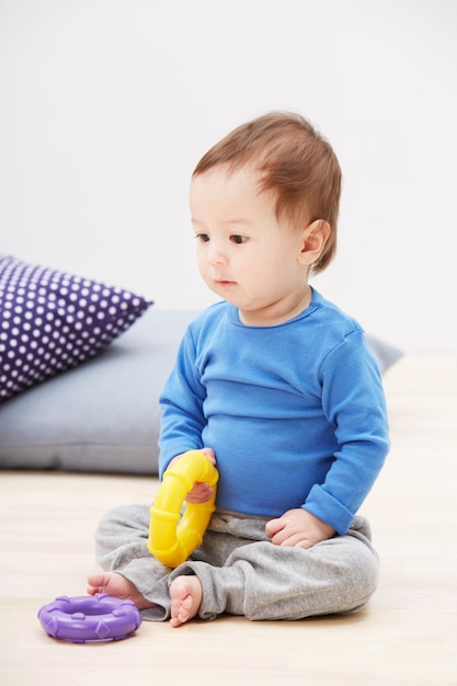 C'est un petit gars espiègle Photo d'un mignon petit garçon assis sur le sol et jouant avec ses jouets
