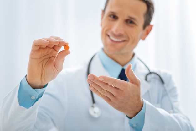 C'est pour toi. Docteur ravi positif gardant le sourire sur son visage et impatient tout en montrant une tablette utile