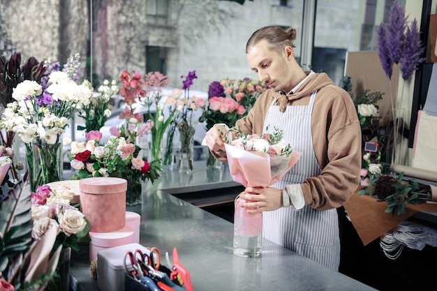 C'est prêt. Fleuriste sérieux s'inclinant la tête tout en regardant les fleurs