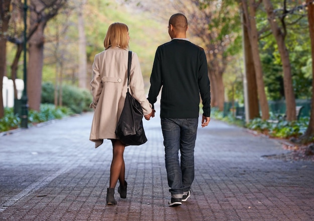 C'est ce qu'est l'amour Vue arrière pleine longueur d'un jeune couple marchant main dans la main dans un parc