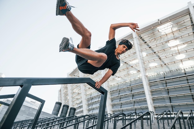 Est-ce que le parkour Un jeune homme en vêtements sportifs s'entraîne à l'extérieur pendant la journée