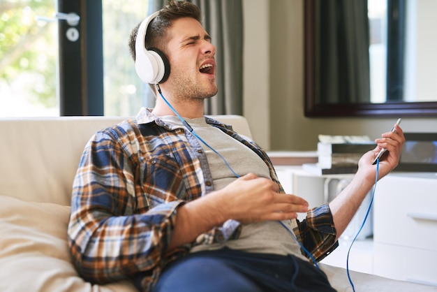 C'est un son de niveau supérieur Photo d'un jeune homme écoutant de la musique avec des écouteurs à la maison