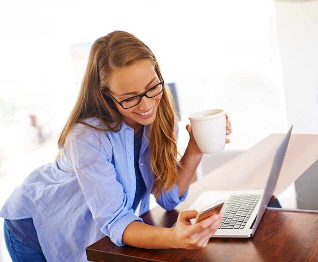 C'est un texte si doux Une jeune femme prenant un café assise avec son ordinateur portable et son téléphone portable