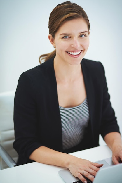 Photo c'est le travail parfait pour moi portrait en studio d'une jeune femme d'affaires travaillant sur son ordinateur portable