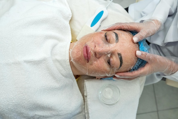 un esthéticien va faire une procédure pour une fille dans une clinique de cosmétologie un patient fait un masque pour les soins de la peau cosmétologie procédures de beauté