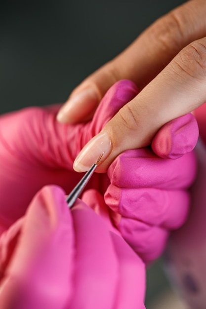 Esthéticienne appliquant des ongles polonais aux ongles de femme. processus de manucure