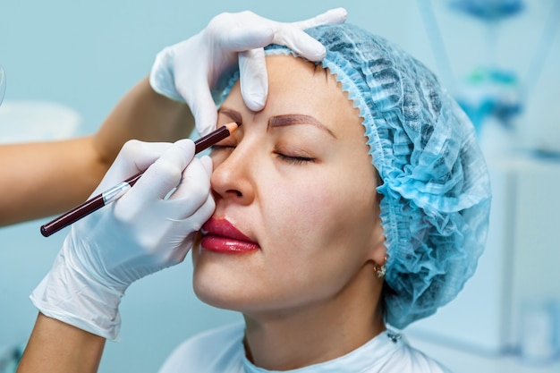 L'esthéticienne applique le balisage sur les sourcils pour le maquillage permanent des sourcils