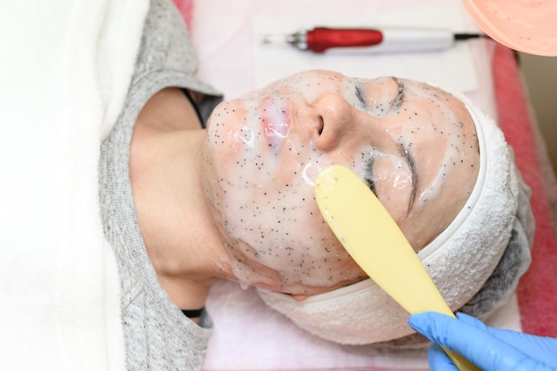 Une esthéticienne applique un masque hydratant blanc sur le visage d'un client