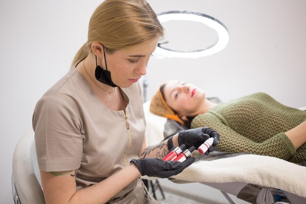 L'esthéticienne choisit le ton de couleur pour le maquillage permanent des lèvres