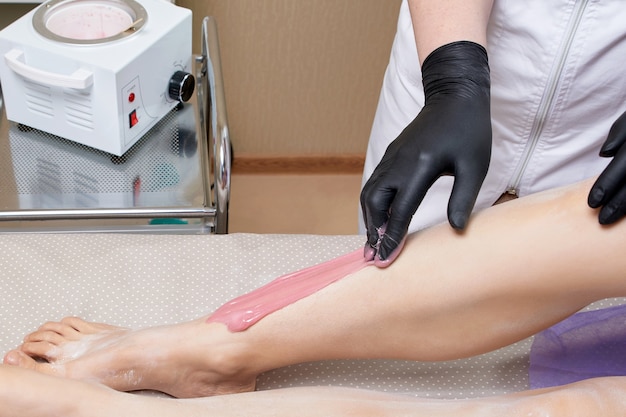 Esthéticienne cosmétologue épilation jambes féminines dans le concept de cosmétologie de salon de beauté spa centre