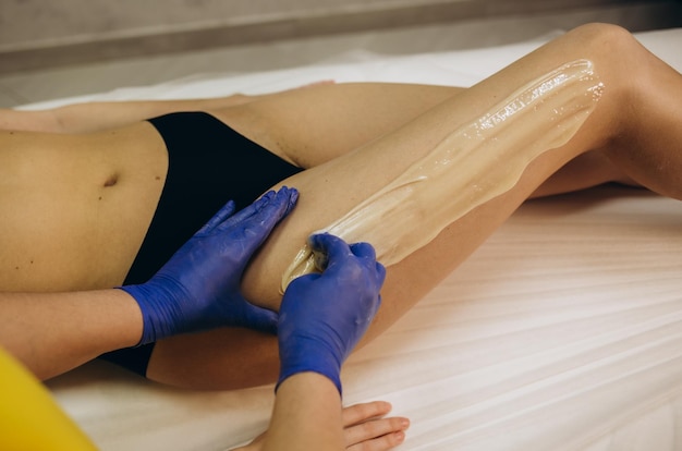 Esthéticienne cosmétologue épilation jambes féminines dans le concept de cosmétologie de salon de beauté spa centre