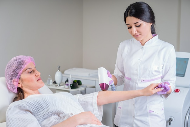 Esthéticienne faisant l'épilation sur la belle main féminine dans un centre médical. Femme recevant des cheveux laser