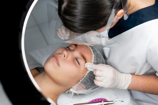 Photo esthéticienne faisant une procédure de microblading sur une femme