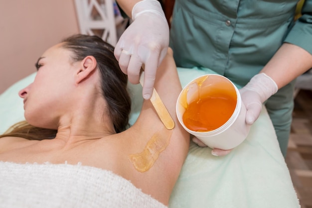 Une esthéticienne fait une épilation à la pâte à sucre sous les aisselles dans un salon de beauté Cosmétologie esthétique féminine