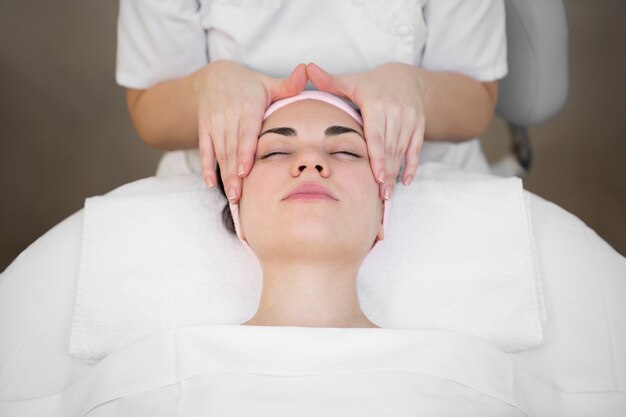 L'esthéticienne fait un massage professionnel du visage du cou et des épaules pour une jeune fille dans le salon Spa.