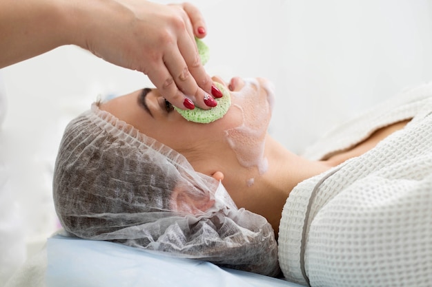 Photo l'esthéticienne fait le nettoyage et l'exfoliation du visage pour une belle fille. salon de beauté.