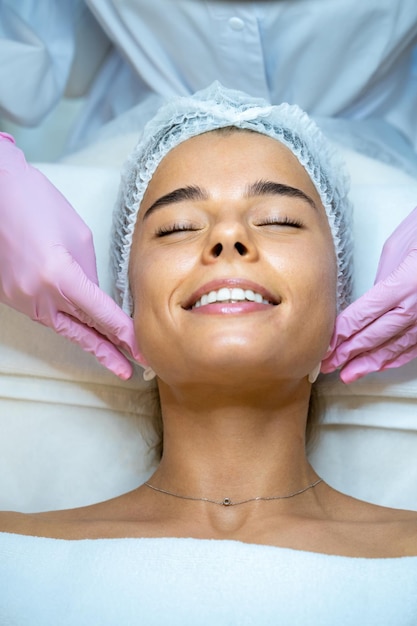 Une esthéticienne inconnue, un médecin, un nettoyage de la peau d'un client, un massage facial à une patiente.
